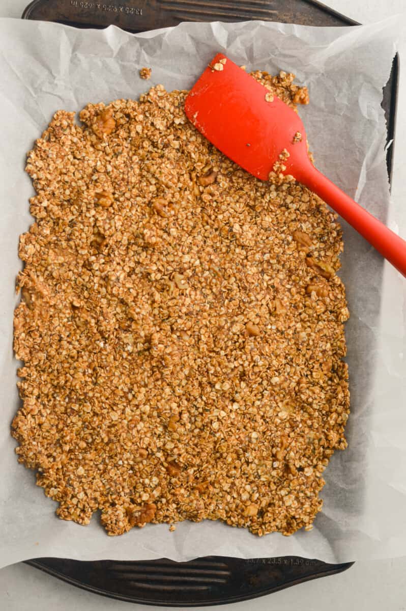 Pressing granola into tray with red spatula.