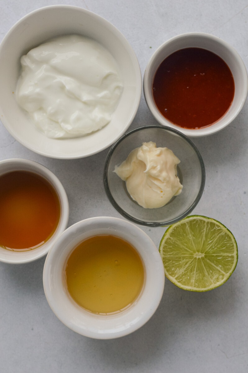 Ingredients including greek yogurt, mayonnaise, honey, sesame oil, sriracha and lime juice.