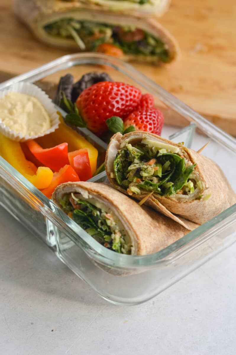 Adult lunchable with chicken spinach wrap, strawberries, veggies and hummus.