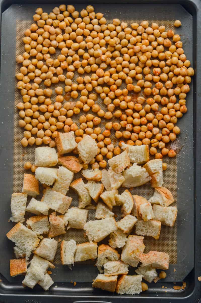 Roasting chickpeas and sourdough croutons on a pan.