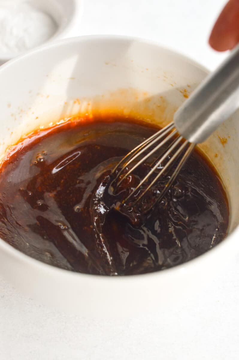 Whisking honey, garlic, ginger, sesame oil, and soy sauce in a bowl.
