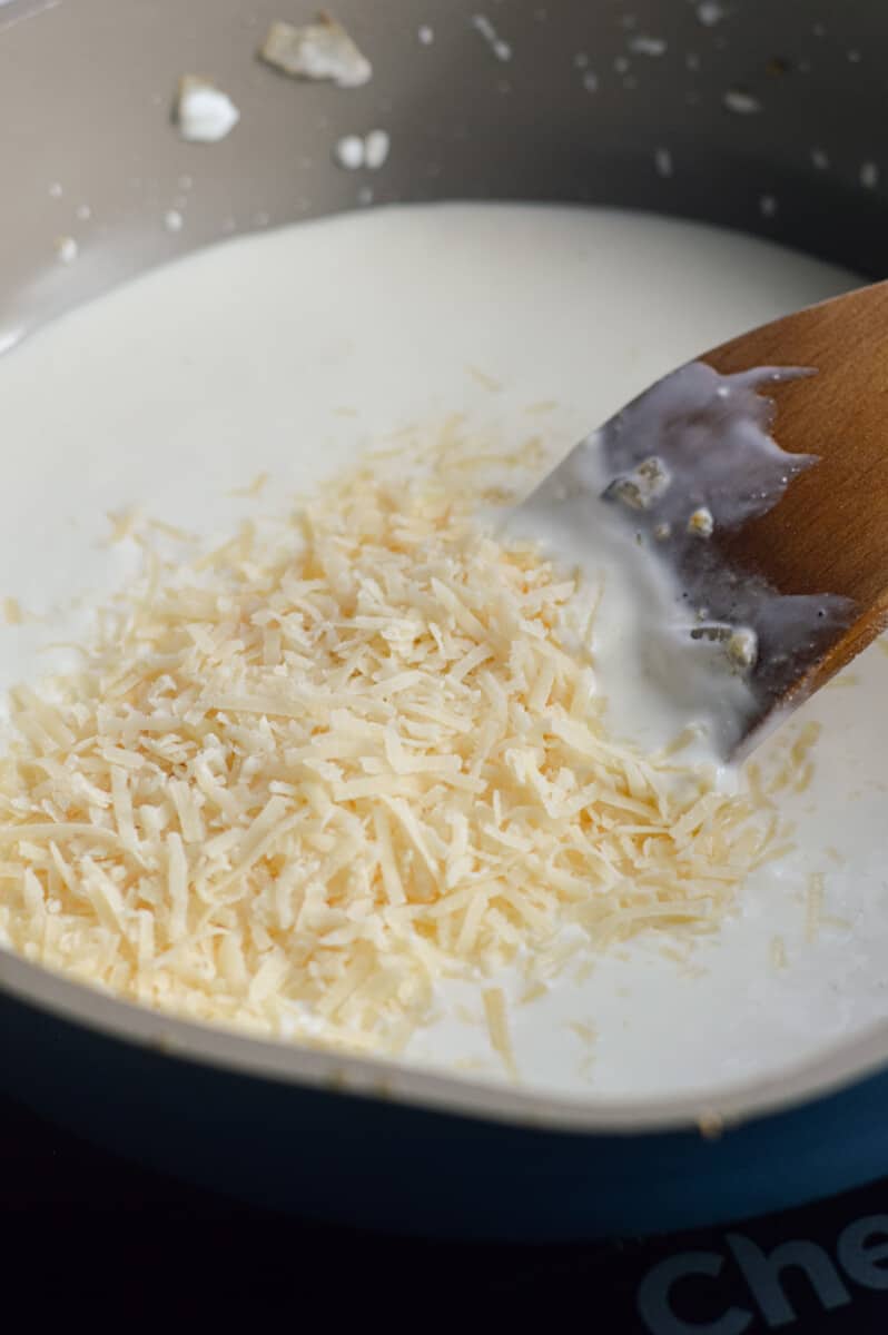 Stirring parmesan cheese into pasta sauce.