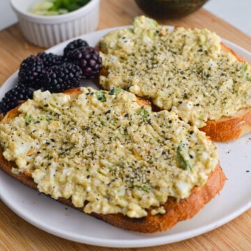 Two slices of avocado cottage cheese toast served with blackberries.
