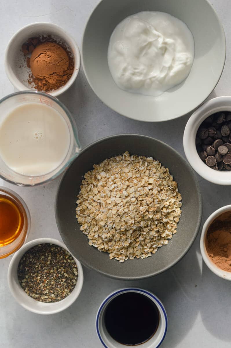 Ingredients include oats, Greek yogurt, milk, chia seeds, salt, chocolate chips, cocoa powder, chocolate protein powder, maple syrup and toppings.