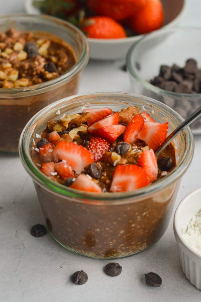 Brownie batter chocolate overnight oats topped with strawberries and chocolate chips.