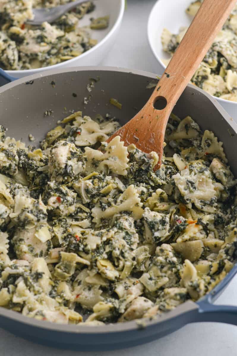 Cooking pasta with artichoke and spinach in a pan.