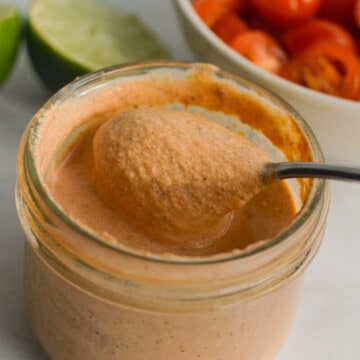 Jar of red creamy salsa dressing with a spoon.
