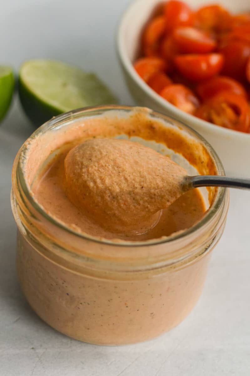 Jar of red creamy salsa dressing with a spoon.