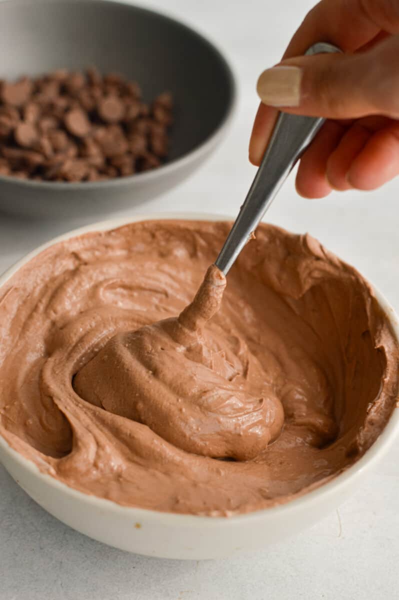 Mixing chocolate Greek yogurt with a spoon.