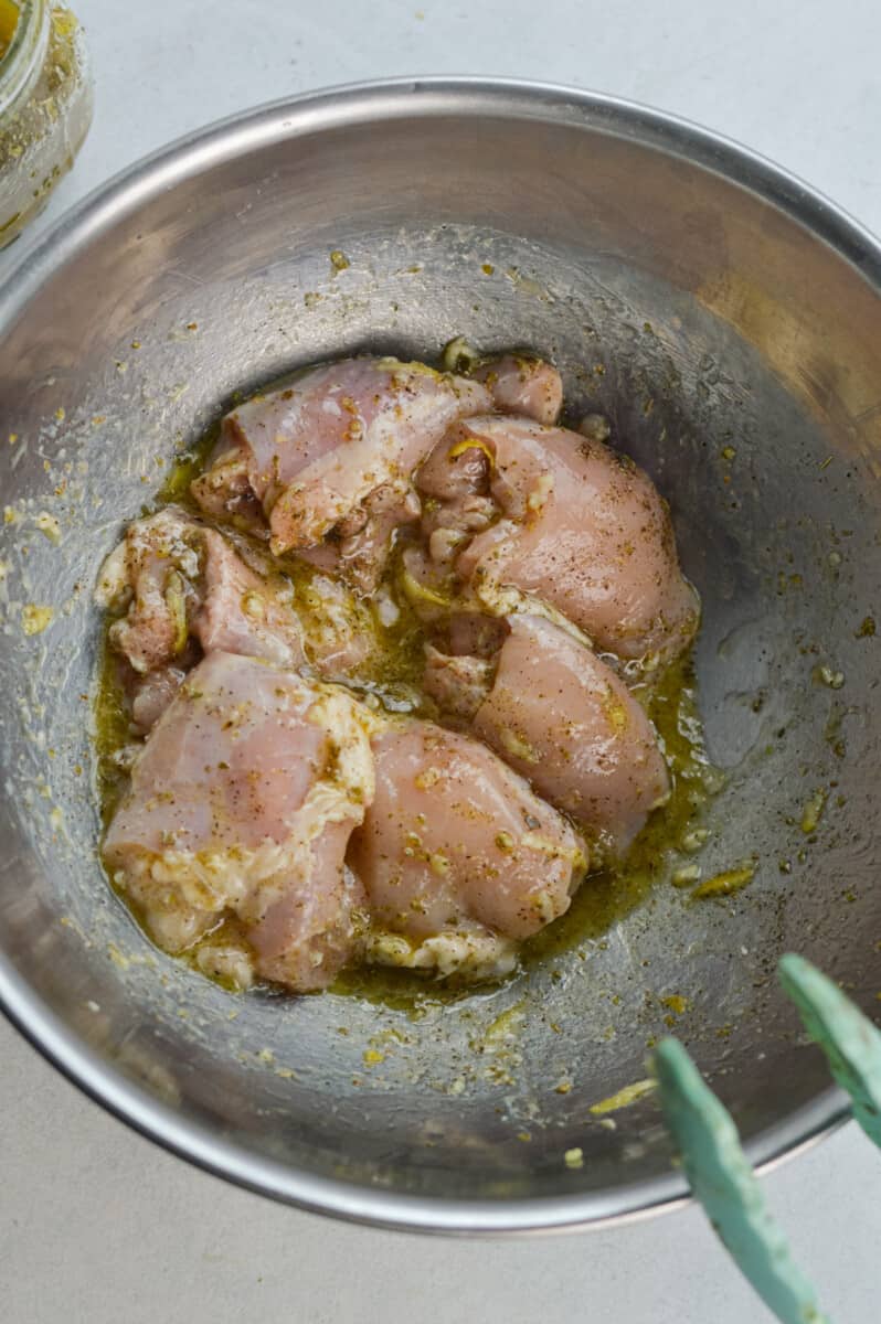 Marinating chicken thighs with olive oil, lemon juice and spices.