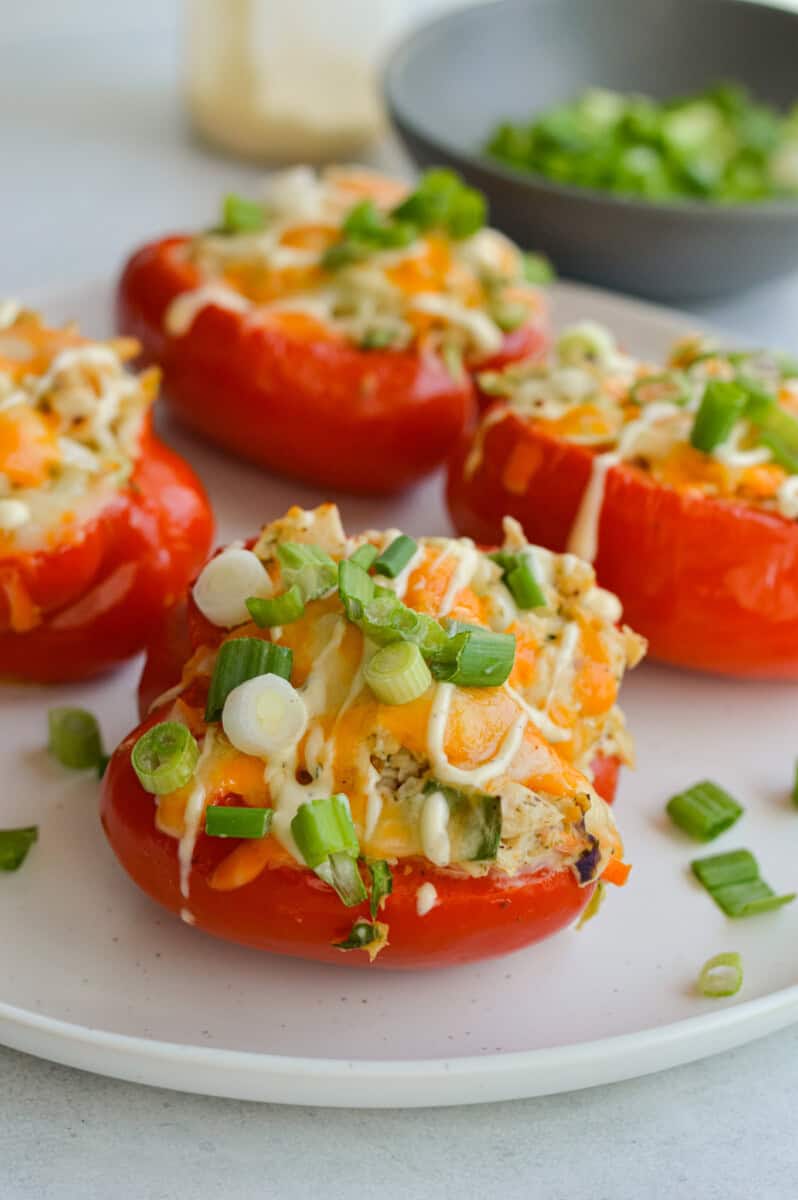 Plate of buffalo ranch tuna stuffed red peppers with cheese and green onions on top.