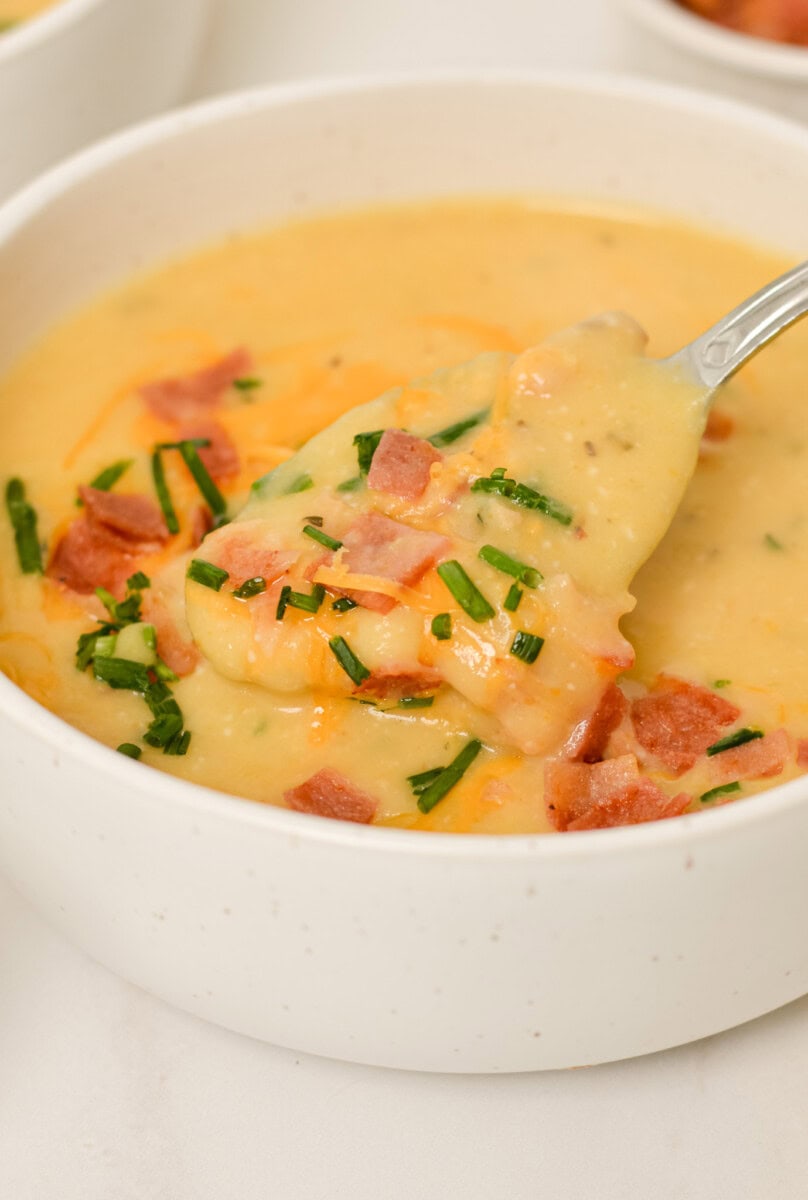 Close up of spoon lifting up soup out of a bowl oaded baked potato soup