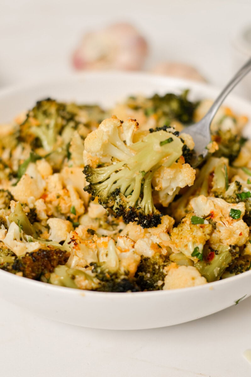 Close up of fork lifting up a piece of broccoli out of a bowl