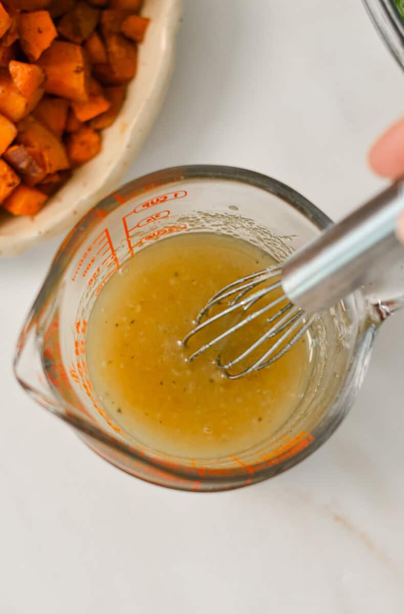 Maple Dijon dressing being whisked in a measuring cup