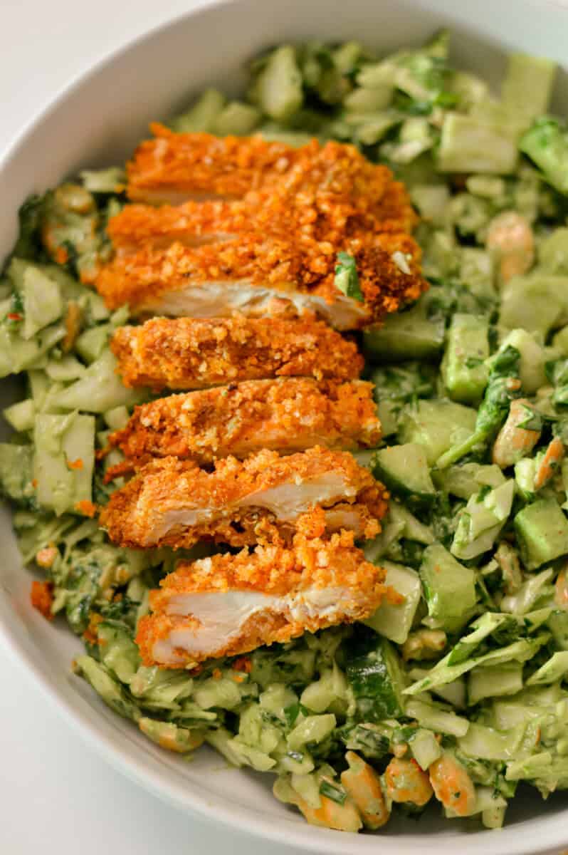 Crispy panko chicken sliced on a green goddess salad