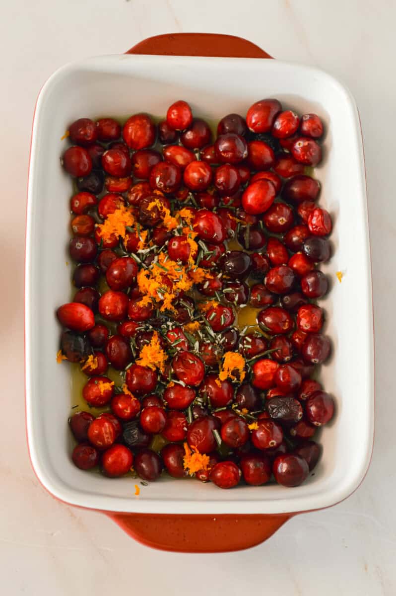 Cranberries, orange juice, orange zest and rosemary in a baking dish
