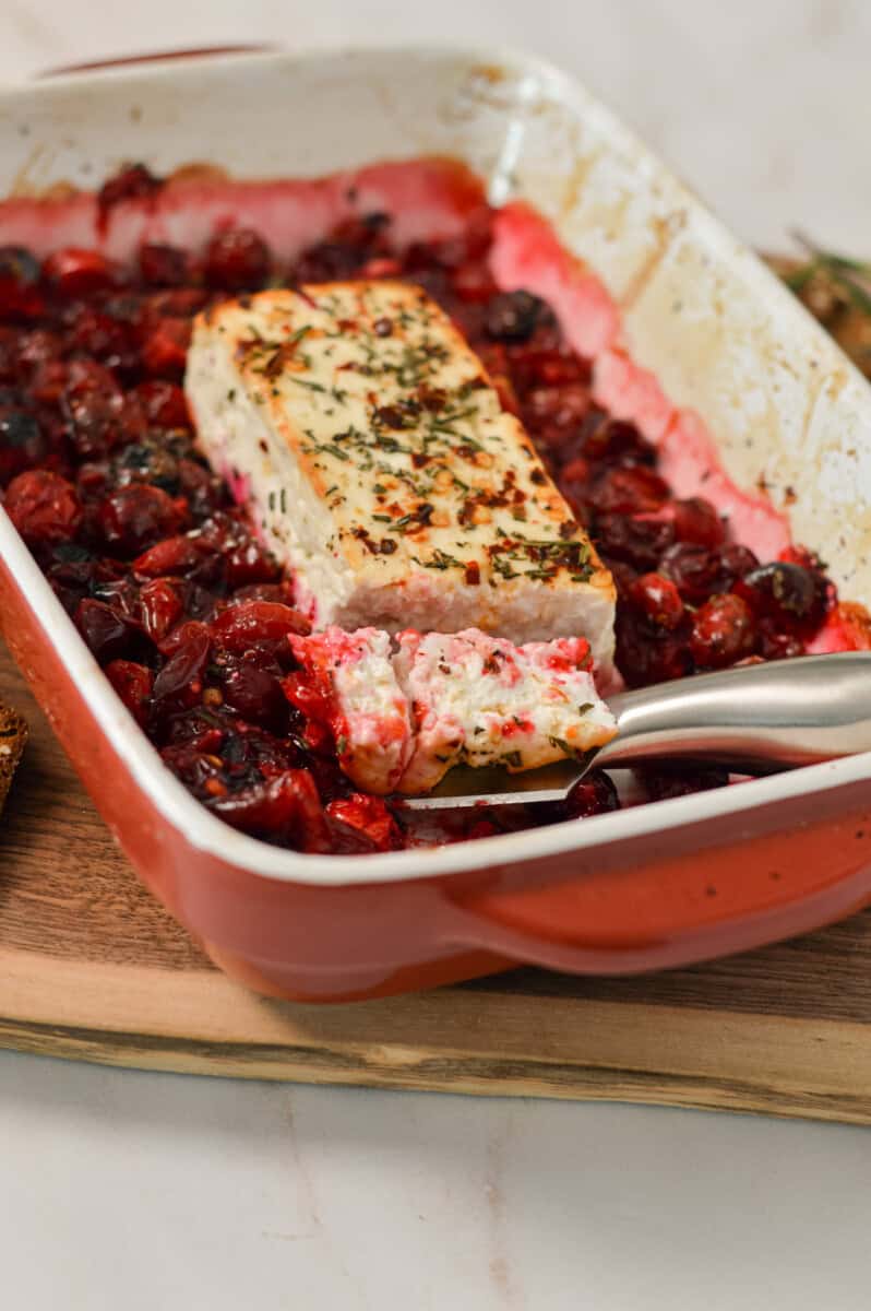 Slicing the baked feta block in the casserole dish