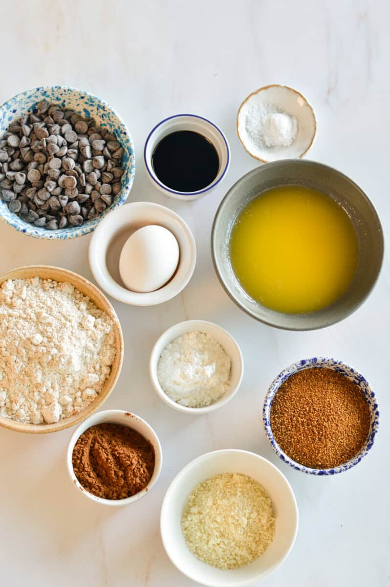 Ingredients for cookies including almond flour, oat flour, butter, egg, chocolate chips, coconut sugar, cocoa powder, vanilla extract, and salt
