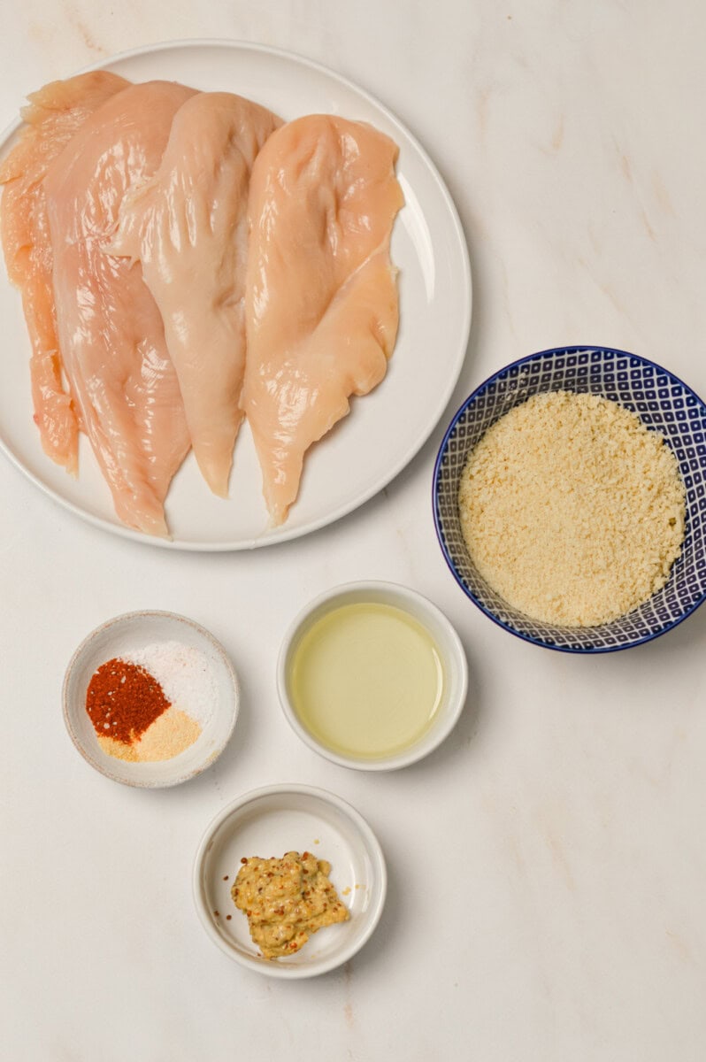 Ingredients for crispy chicken including chicken breasts, panko breadcrumbs, spices, dijon mustard and olive oil