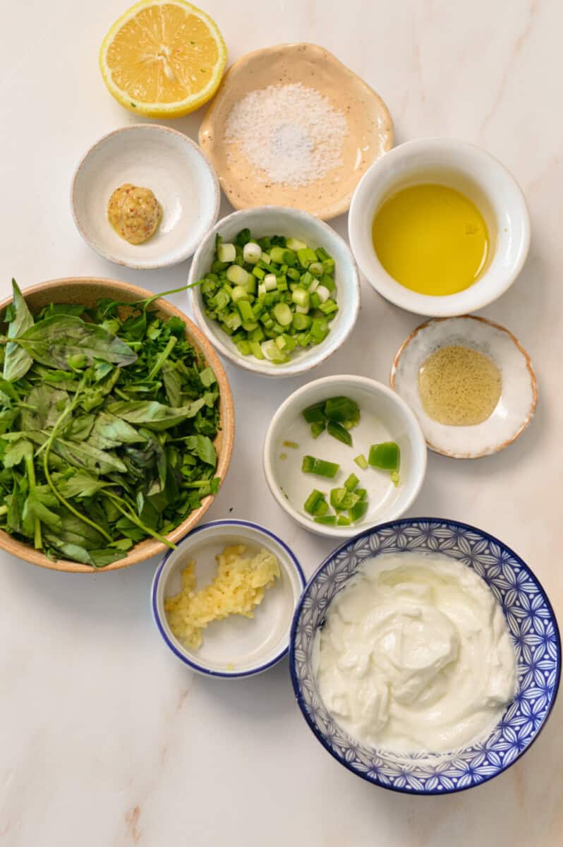 Ingredients for green goddess dressing including Greek yogurt, olive oil, lemon, dijon mustard, honey, herbs of choice, spinach, green onion, salt and jalapeno