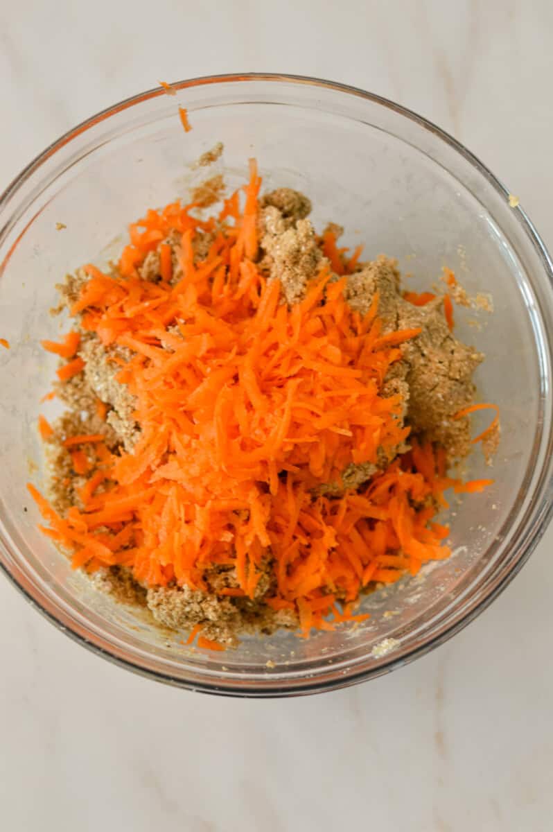Shredded carrots added to the mixing bowl