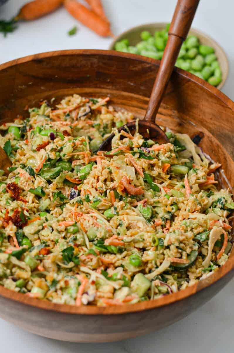 Salad tong lifting up salad out of a large bowl
