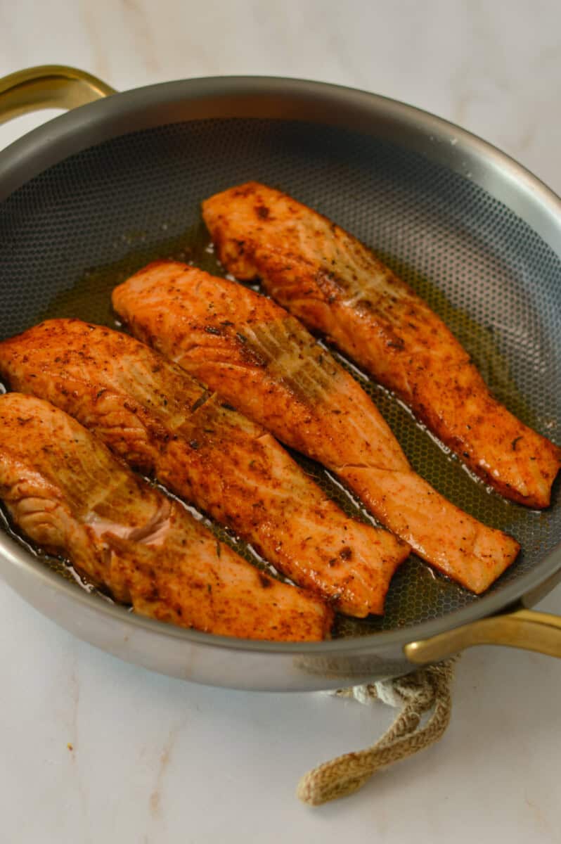 Salmon filets being seared in a pan