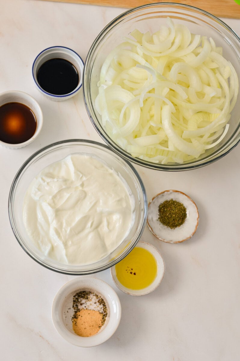 Ingredients for caramelized onion dip including onion, Greek yogurt, spices, worcestershire sauce, and chives