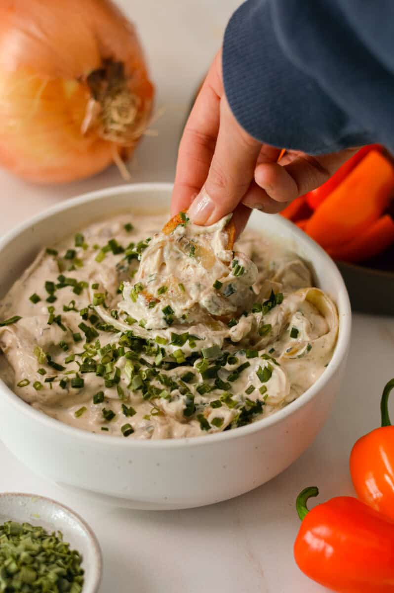 Scooping up french onion dip with a pepper