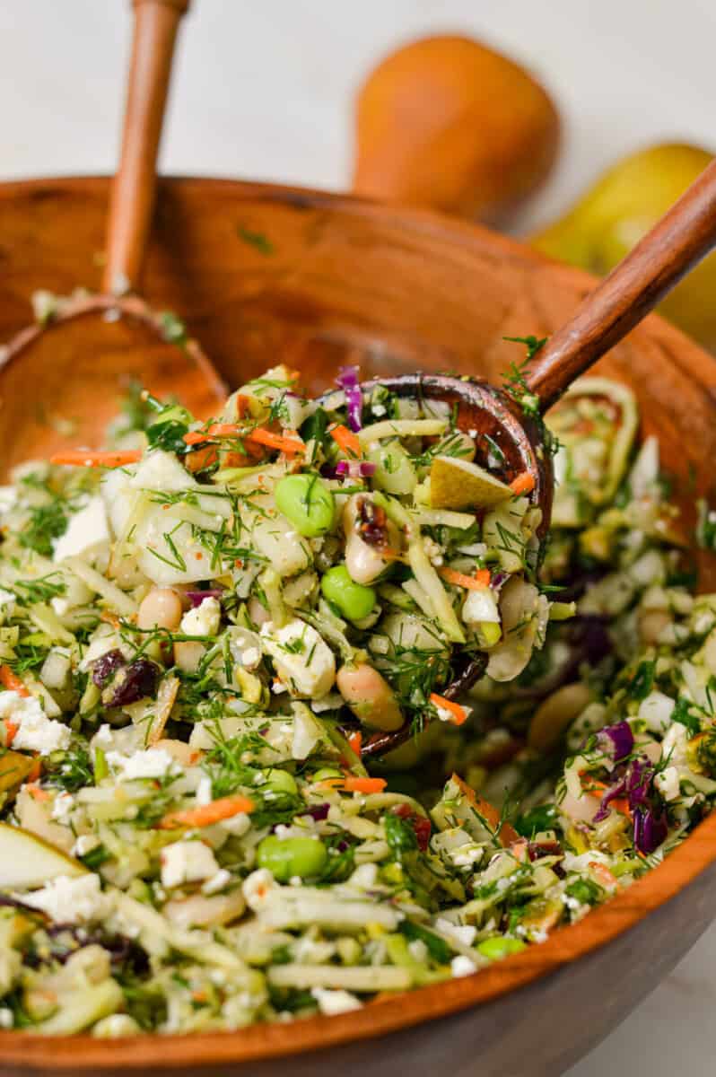 Close up of a salad tong lifting up the pear and fennel salad out of a bowl