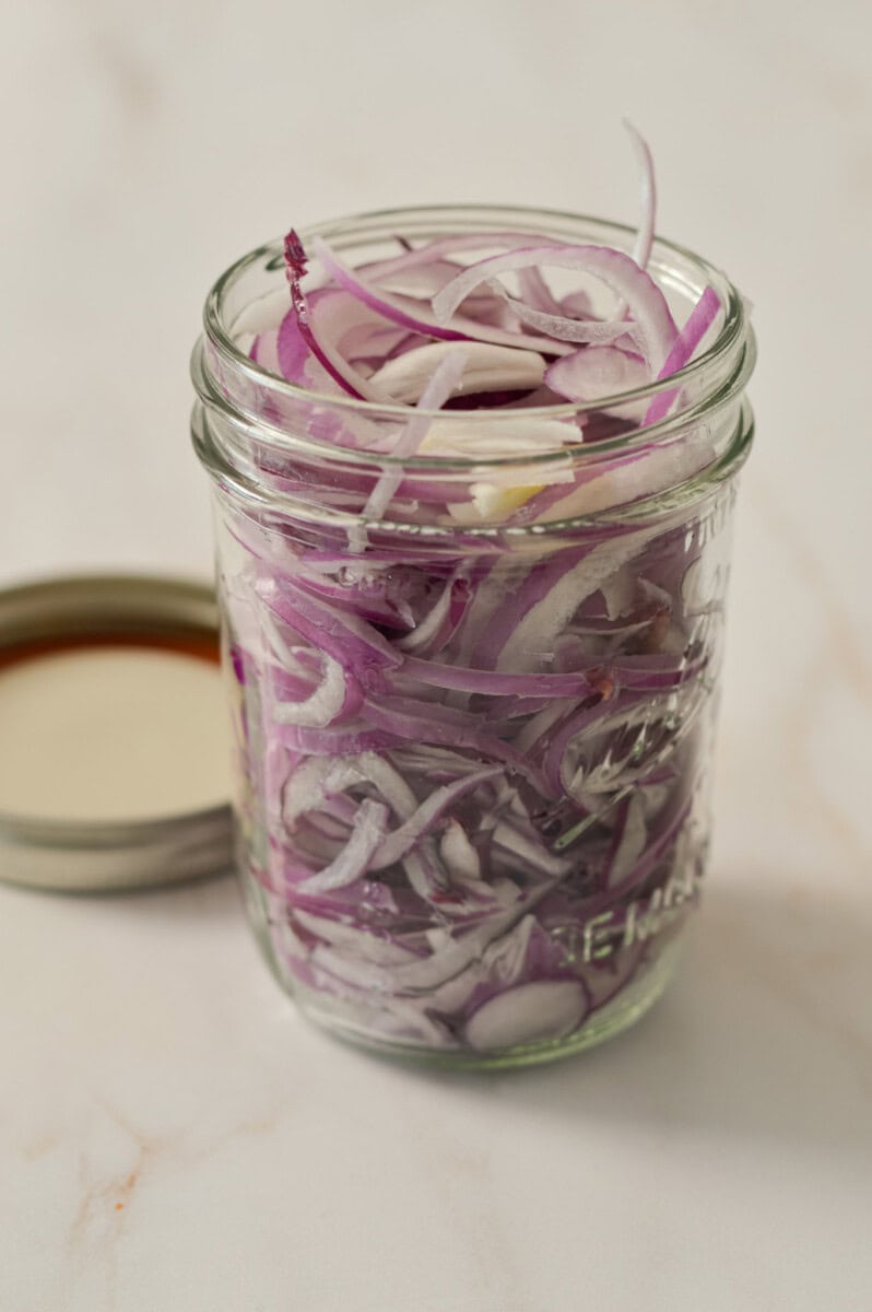 Red onions thinly sliced in a jar