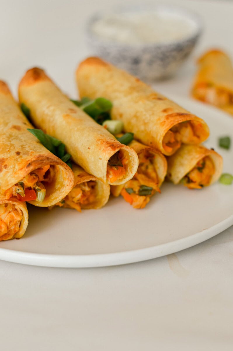 Close up of stacked baked taquitos on a plate