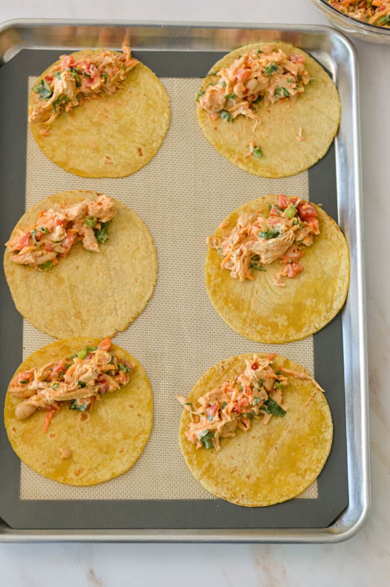 Tortillas on a baking sheet with filling in each