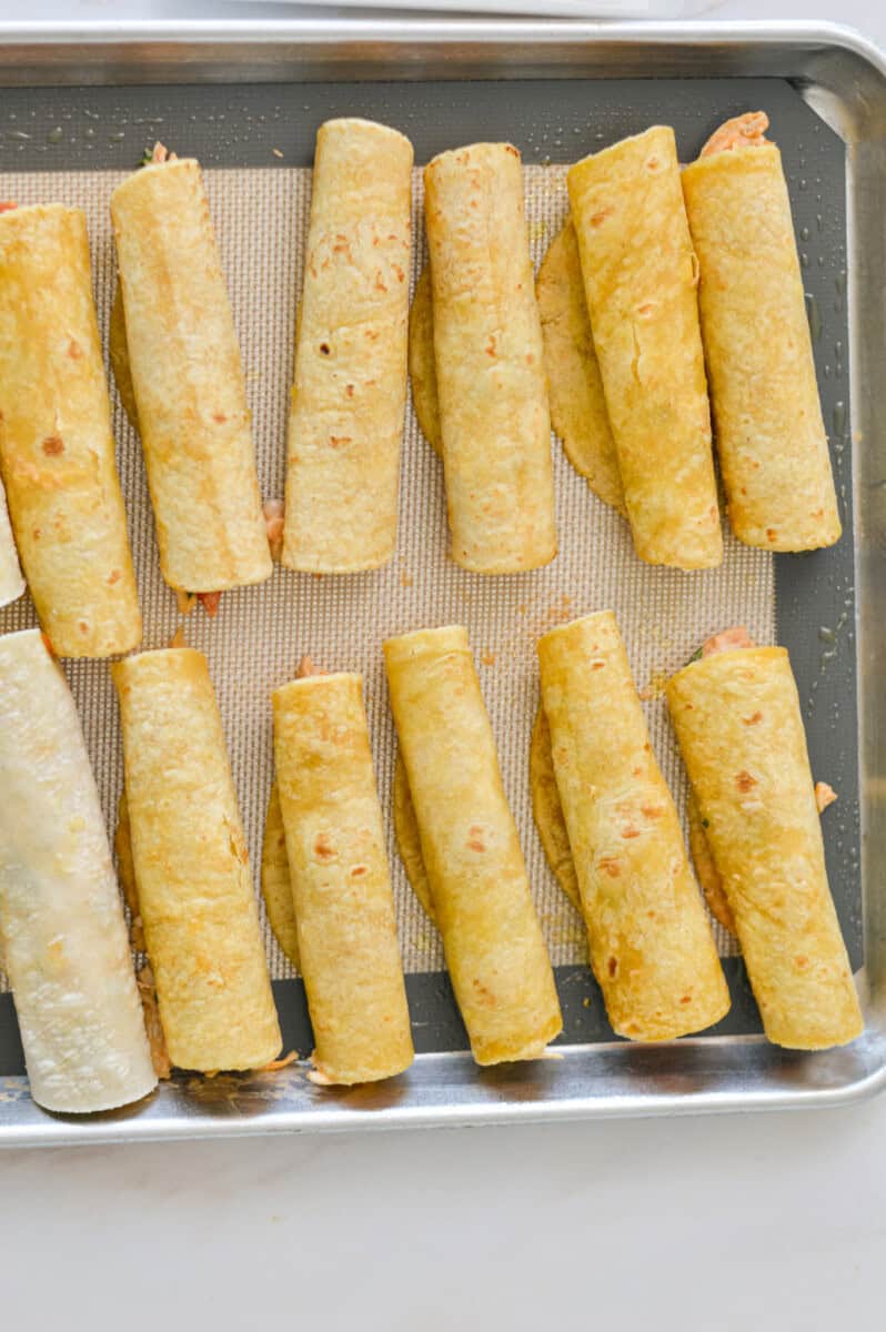 Taquitos rolled up on a baking sheet