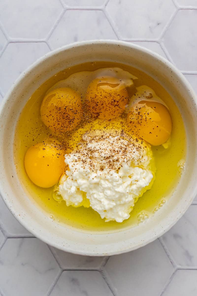 Eggs and cottage cheese in a bowl with salt and pepper.