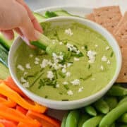 Cucumber dipping in green pea hummus.