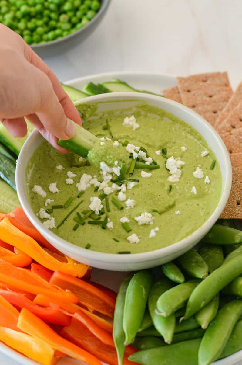 Cucumber dipping in green pea hummus.