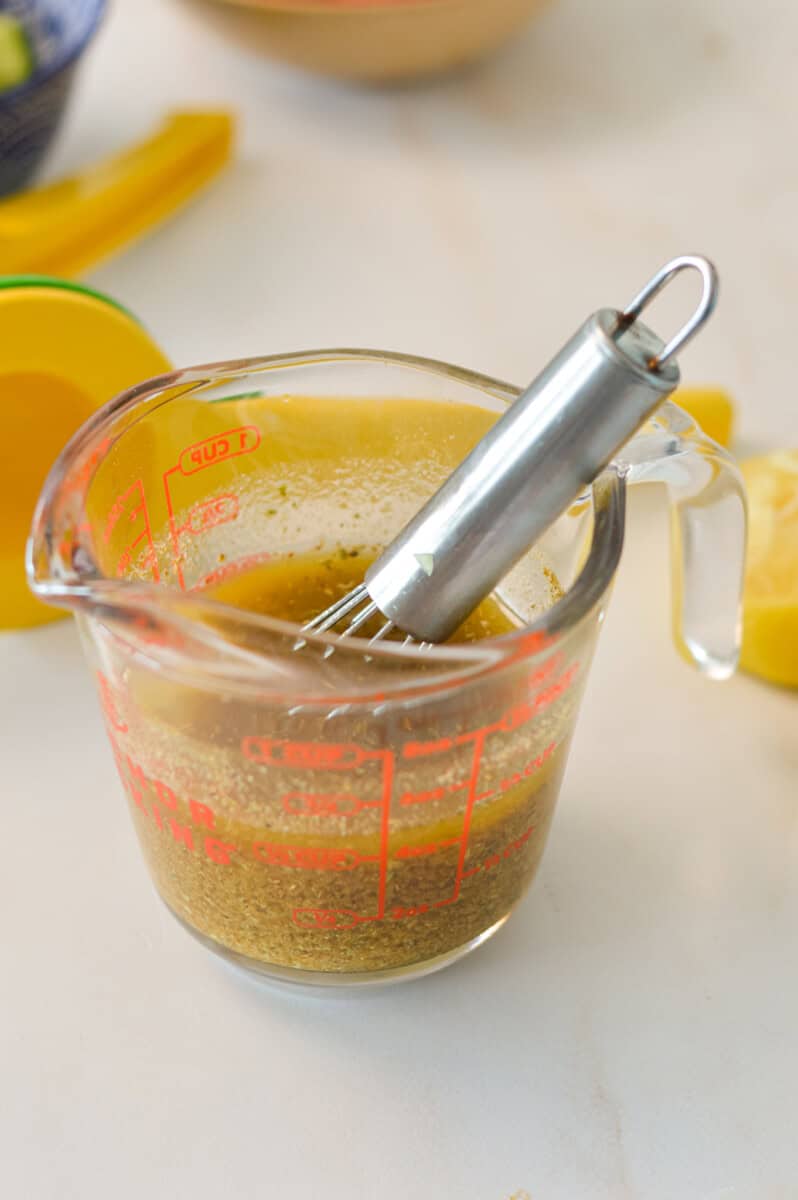 Salad dressing in a measuring cup with a whisk.