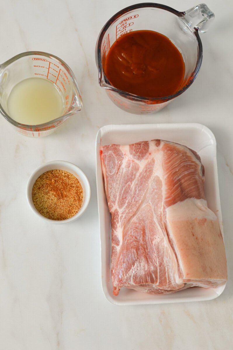 Ingredients for pork including pork shoulder, BBQ sauce, apple cider vinegar and chicken broth