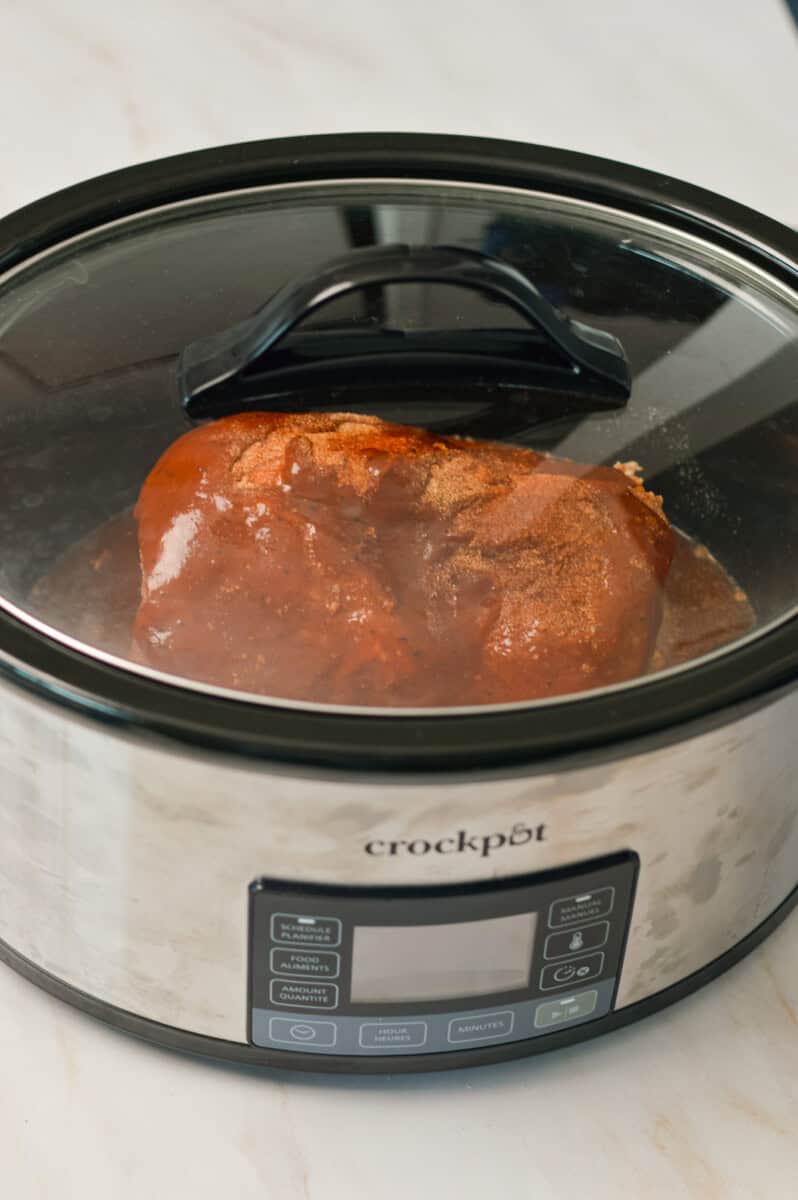 Lid closed on the slow cooker with pork inside.