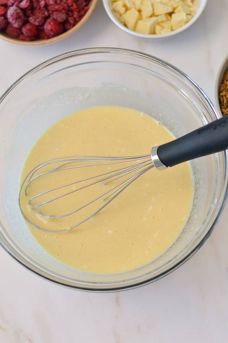 Wet ingredients combined in a bowl with a whisk.