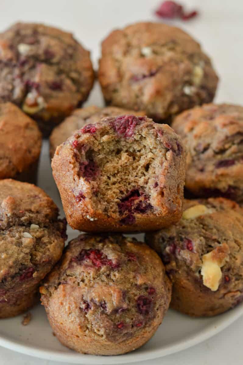 Muffins on a plate with a bite taken out of one muffin.