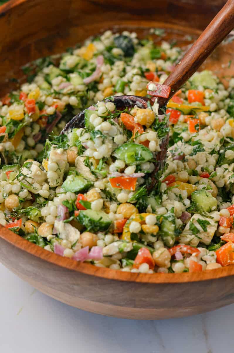 a fully mixed salad with a wooden spoon for serving