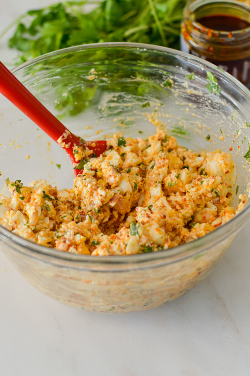 Egg salad being stirred in a mixing bowl.