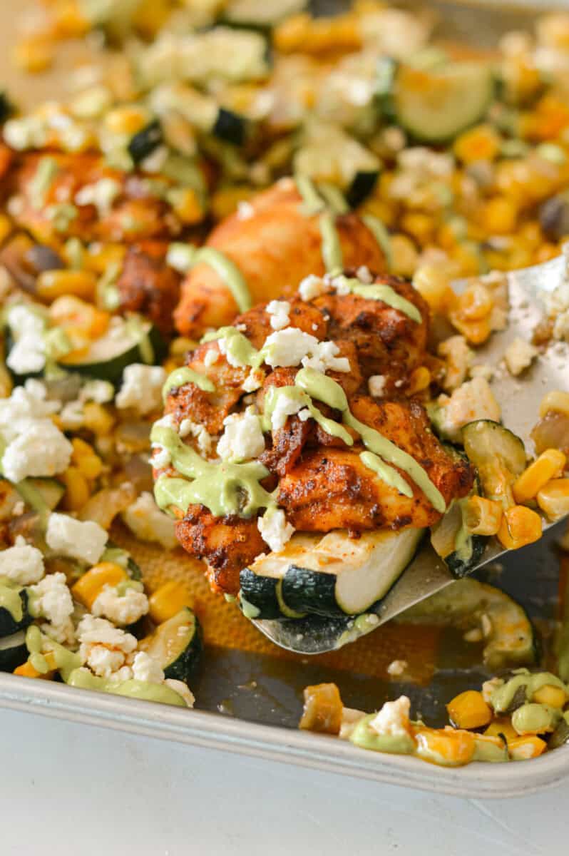 Lifting up a piece of the Mexican street corn chicken off of the sheet pan.