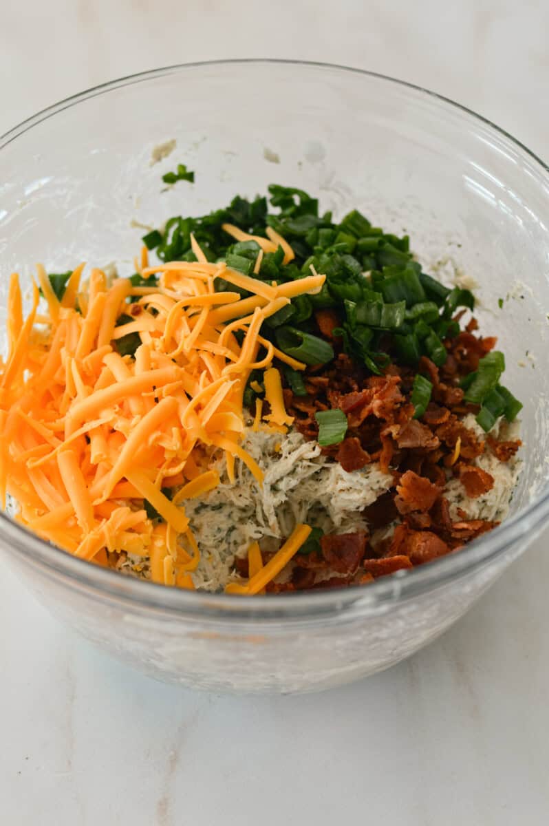 Shredded cheddar cheese, bacon and green onion added to the bowl.