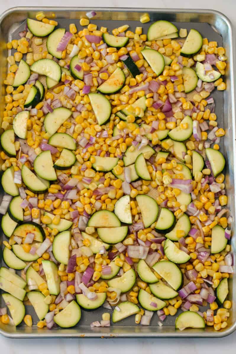 Zucchini, corn and red onion on the sheet pan.