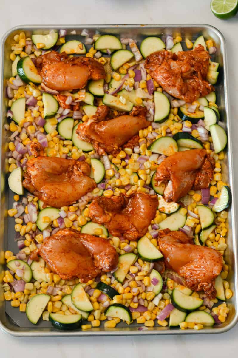 Marinated chicken thighs added to the street corn sheet pan.