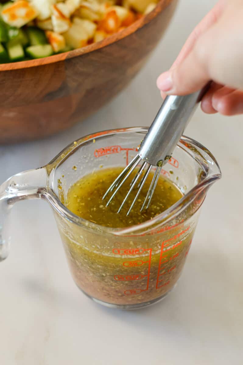 Taverna salad dressing being whisked in a measuring cup.