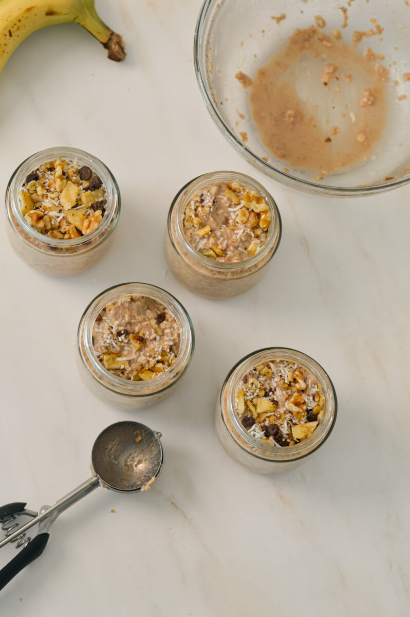 Birdseye of overnight oats being portioned into glass jars.